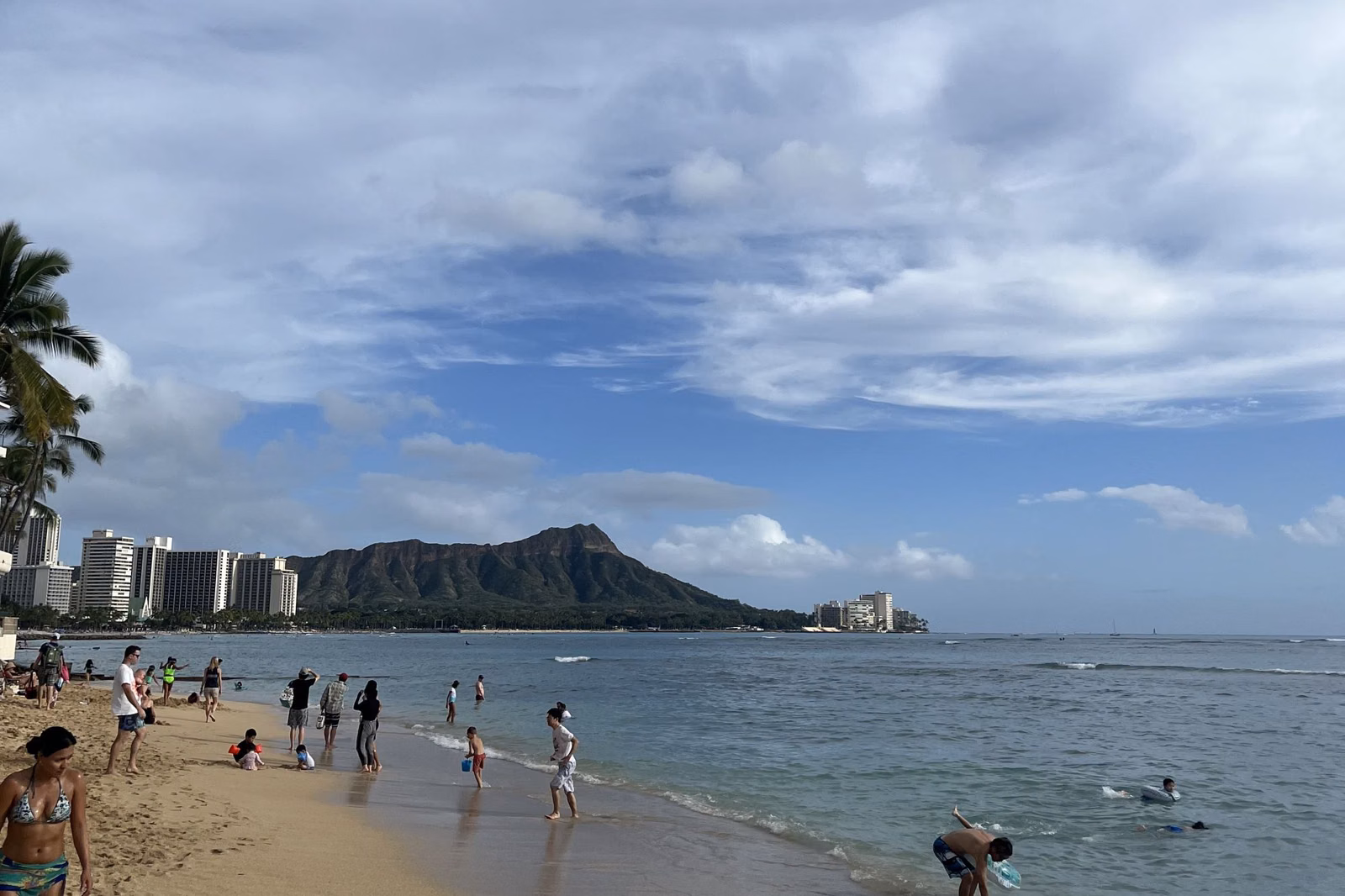 Diamond Head on the horizon beyond a Waikīkī beach and shallow water