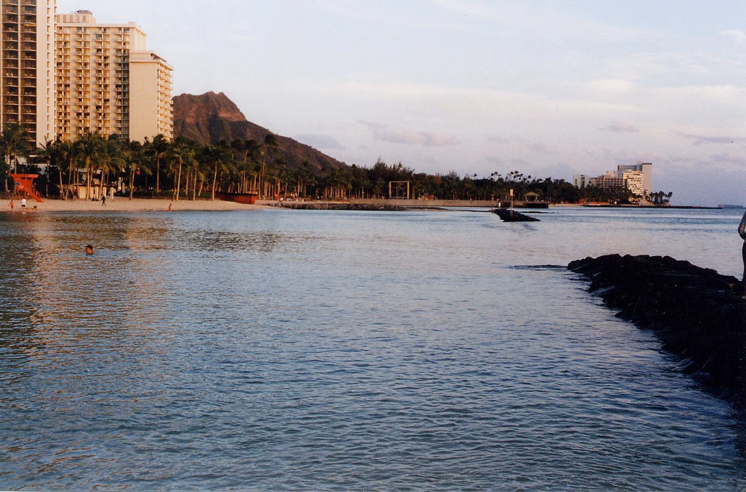 Calm water off Waikīkī at sunset with hotel towers and Diamond Head