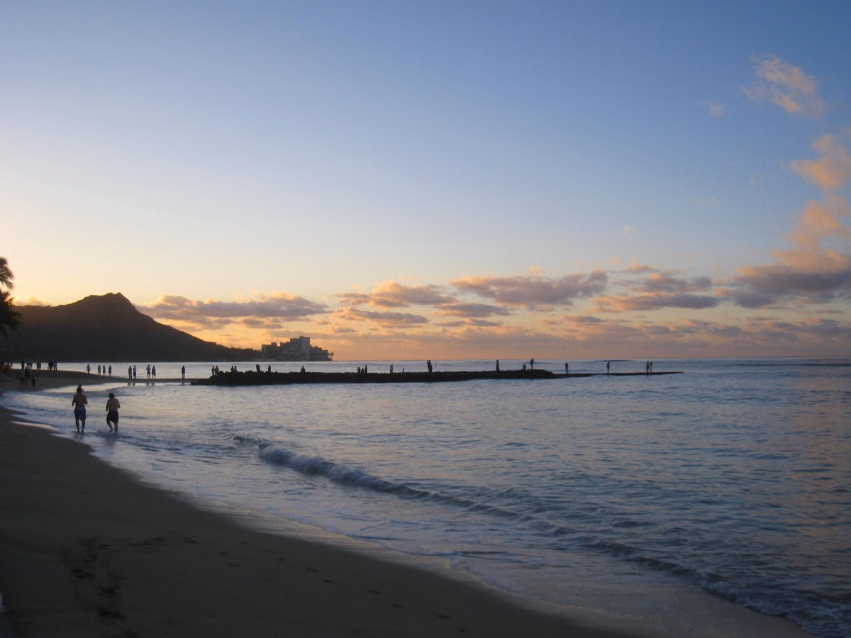 Diamond Head silhouetted at dusk across the water from Waikīkī Beach