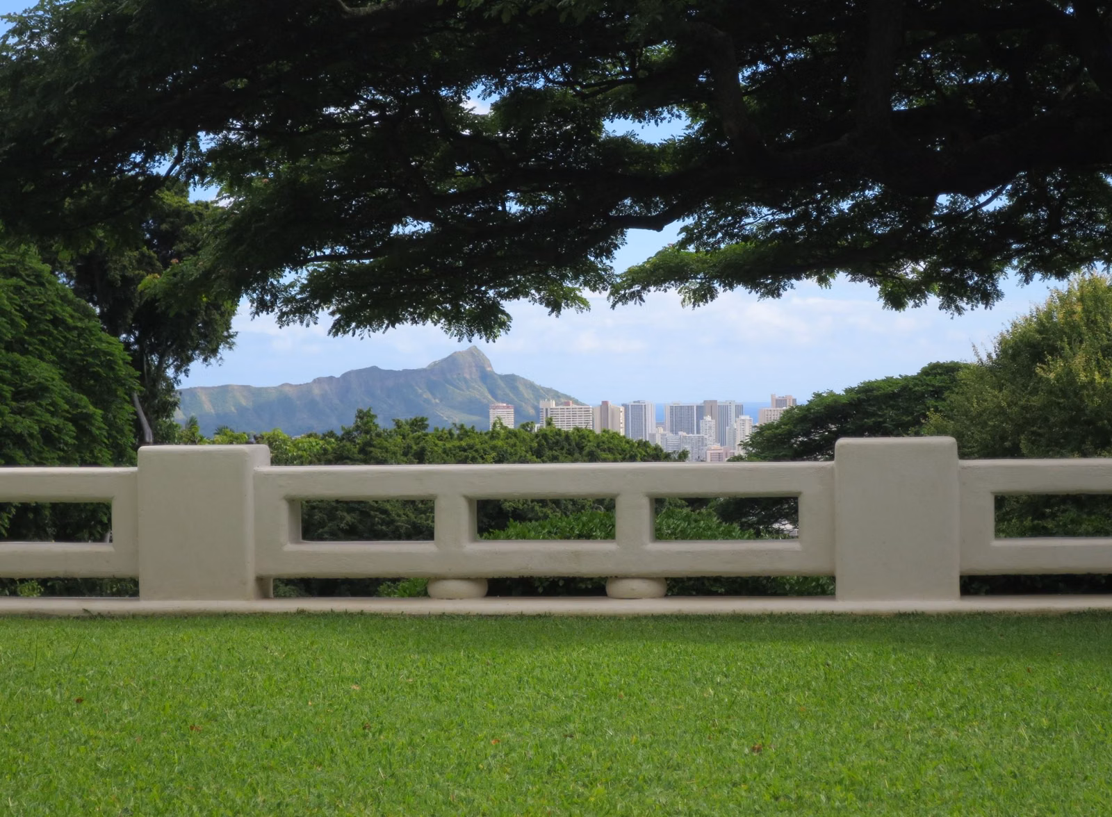 Diamond Head and Waikīkī towers seen beyond a garden balustrade and lawn in Makiki Heights, Honolulu