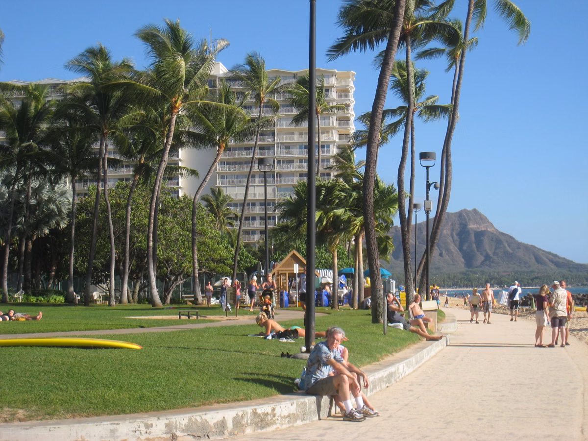 A palm-lined beachfront walkway in Waikīkī with Diamond Head in the distance