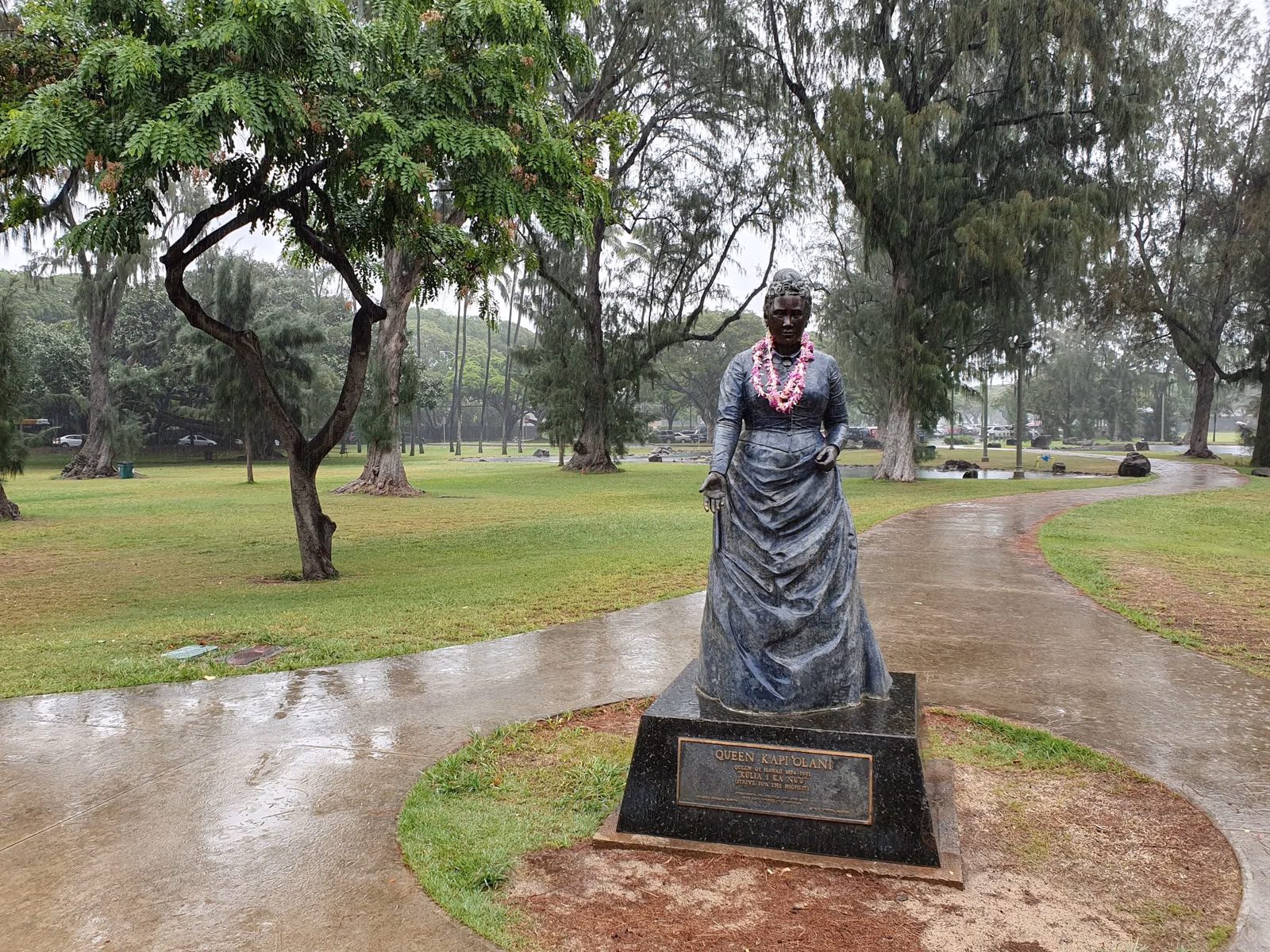 The bronze statue of Queen Kapiʻolani, draped with lei, on a path in Kapiʻolani Park