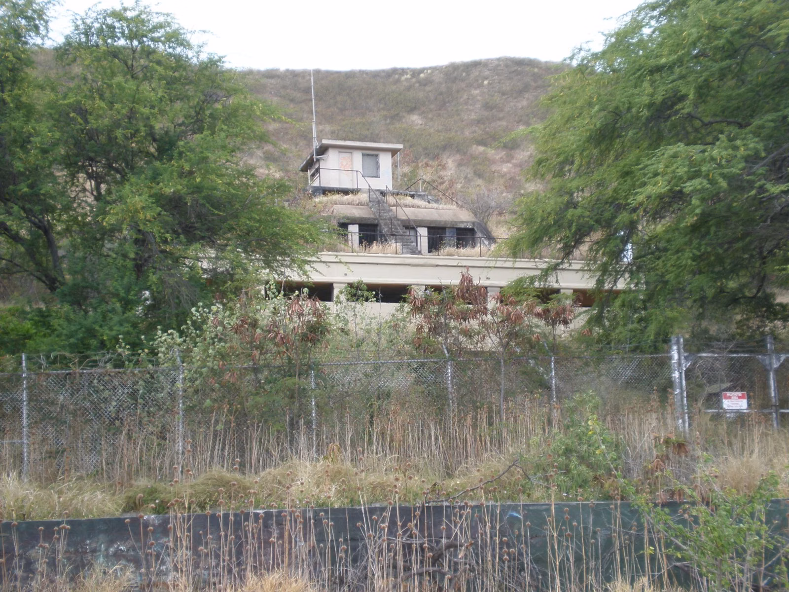 An old military bunker on the outside slope of Diamond Head, behind a chain-link fence