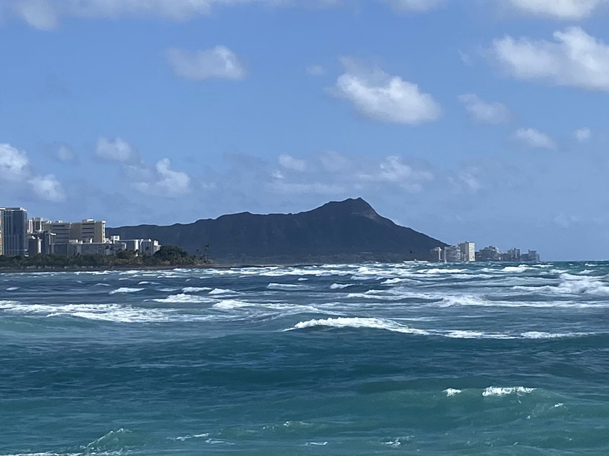 Diamond Head rising above the Waikīkī shoreline, seen across open water from the south shore of Oʻahu